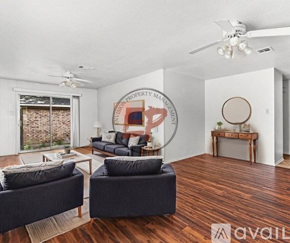 A living room with a couch, chair, and a fan.