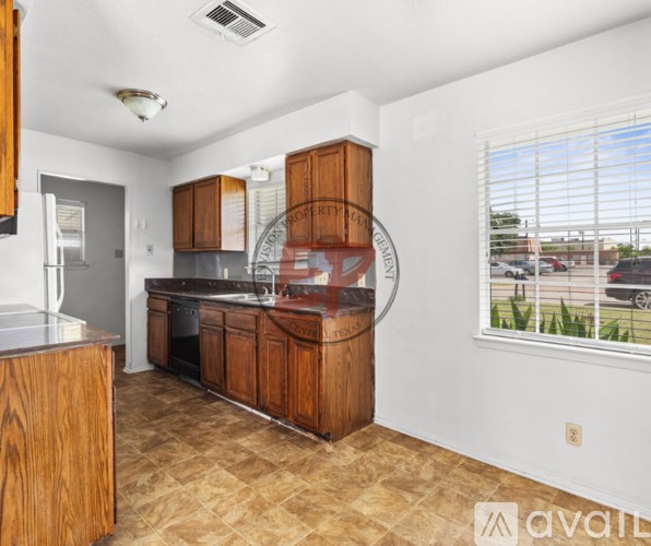 A kitchen with wooden cabinets and a tiled floor.