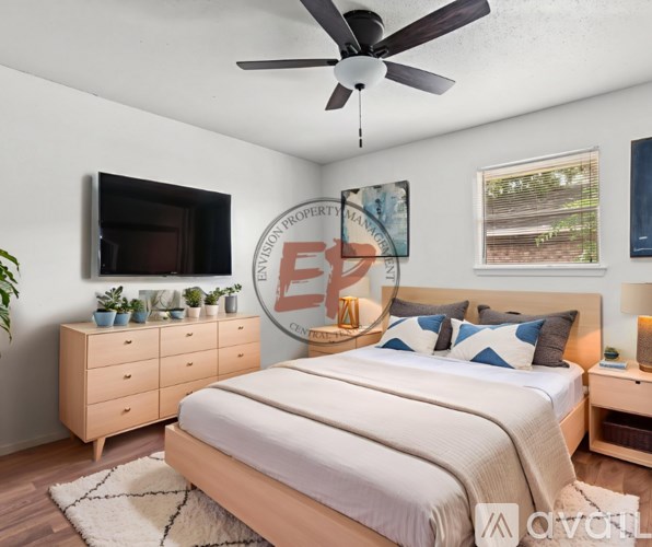 A bedroom with a large bed, a ceiling fan, and a dresser with a mirror above it.