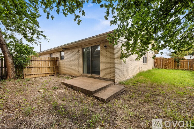 A house with a brown fence and a tree in front.