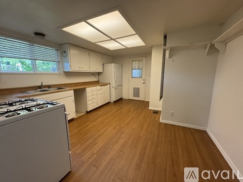 A kitchen with a gas stove and wooden floors.