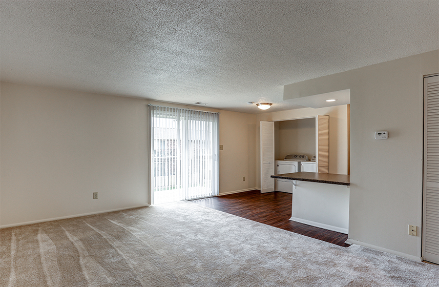 A sparsely furnished living room with a sliding glass door leading to a balcony.