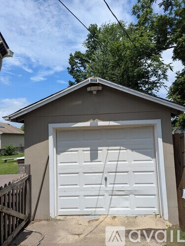 A garage with a white door is situated in front of a house.