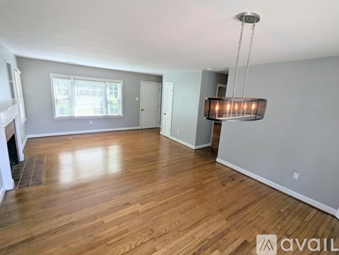 A spacious room with wooden flooring and a hanging light fixture.