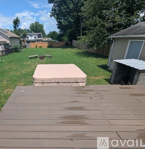 A wooden deck leads to a covered patio in a backyard.