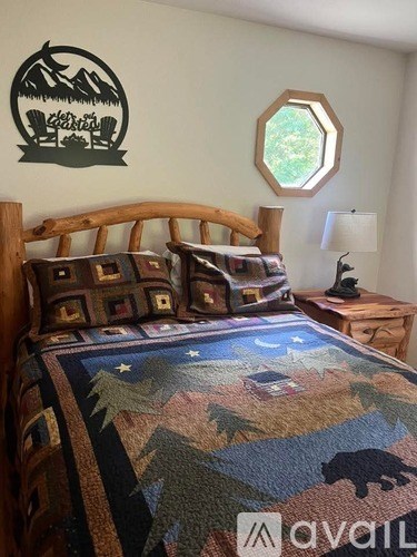 A bed with a bear design on the bedspread is in a room with a mountain logo on the wall.