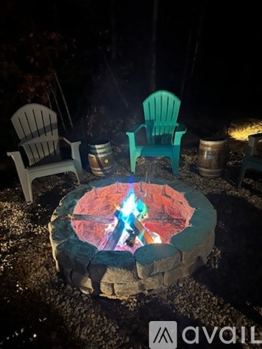 A fire pit with a blue flame in the middle and two chairs around it.