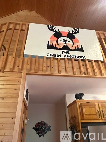 A sign that says "The Cabin Kingdom" hangs on a wooden wall.
