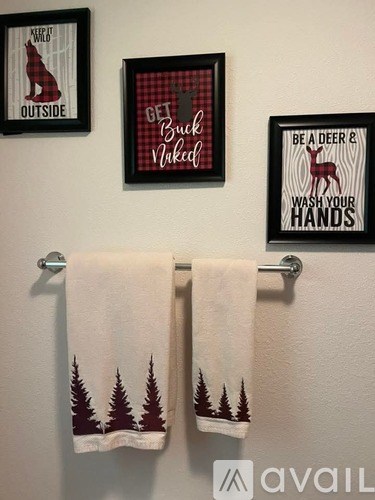 A bathroom with a towel and three framed pictures on the wall.