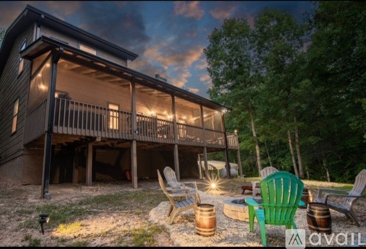 A wooden cabin with a porch and a green chair in front of it.
