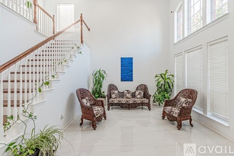 A living room with a staircase and a large painting on the wall.