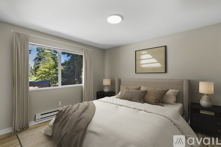 A bedroom with a large bed and a window with curtains.