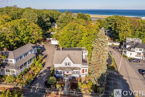 A bird's eye view of a house surrounded by trees and a parking lot.
