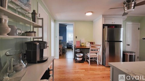 A kitchen with a refrigerator, a dining table with chairs, and a counter with a coffee maker.