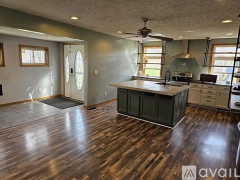 A kitchen with wood flooring and a ceiling fan.
