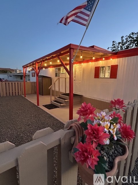 A small building with a flag on top and flowers in a pot.