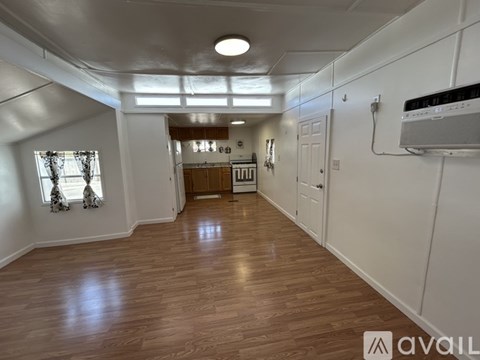 A spacious room with wooden flooring and white walls.