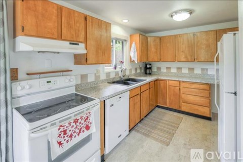 A kitchen with wooden cabinets and a white stove top oven.