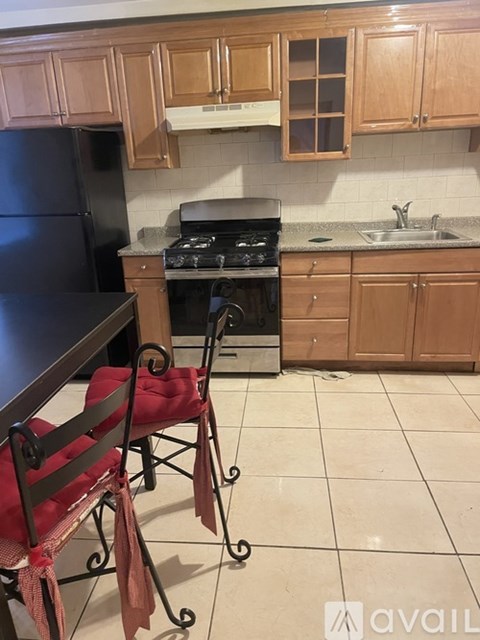 A kitchen with a black fridge, a stove, and wooden cabinets.