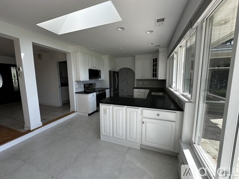 A modern kitchen with white cabinets and black countertops.