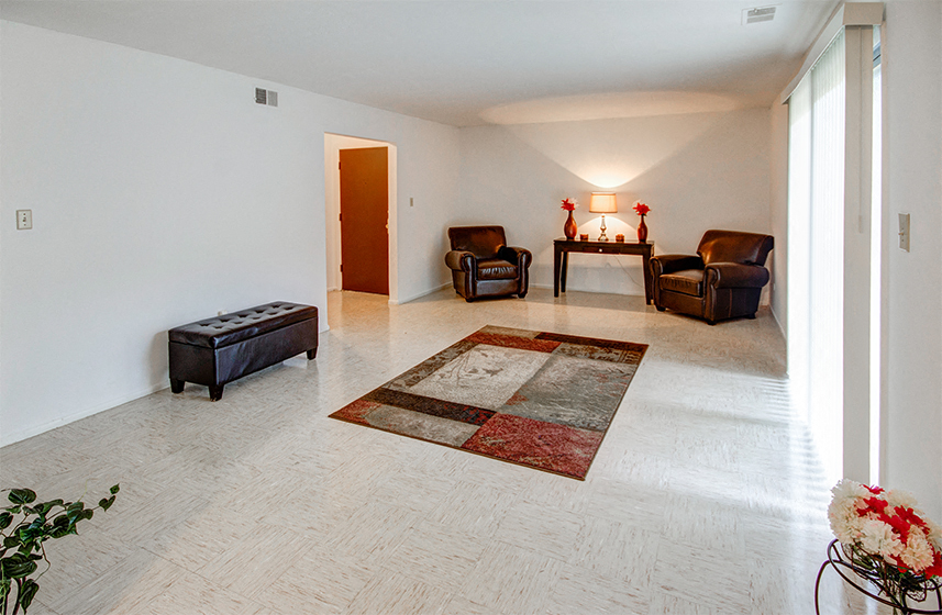 A living room with a rug and three chairs.