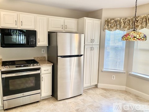 A kitchen with white cabinets and a stainless steel refrigerator.