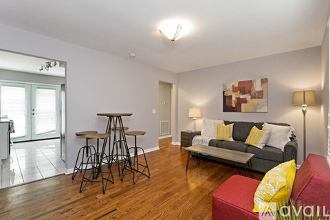 A living room with a grey couch and a red ottoman.