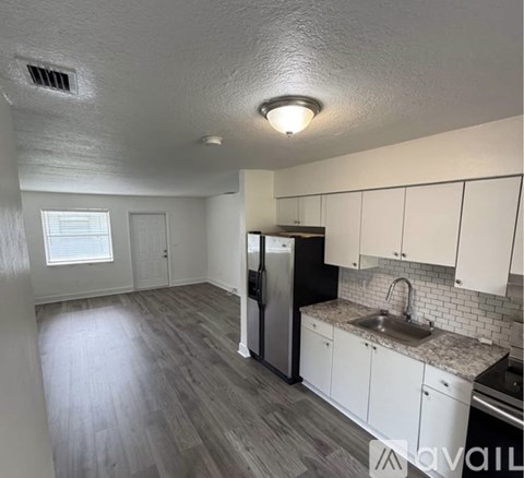 A kitchen with white cabinets and a black refrigerator.