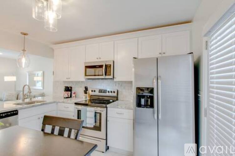 A kitchen with white cabinets and a stainless steel refrigerator.