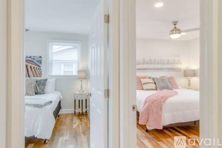 A bedroom with a white bed and a pink blanket.