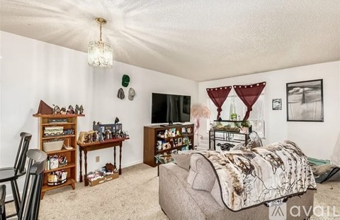 A bedroom with a bed, a chair, a desk, and a bookshelf.