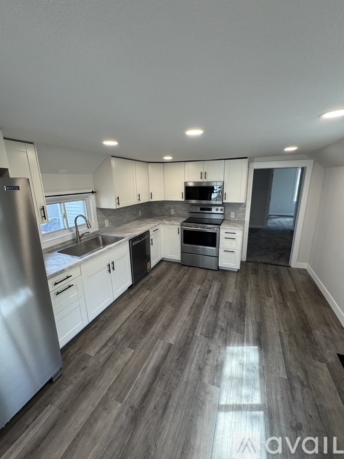 A kitchen with a refrigerator, sink, oven, and microwave.