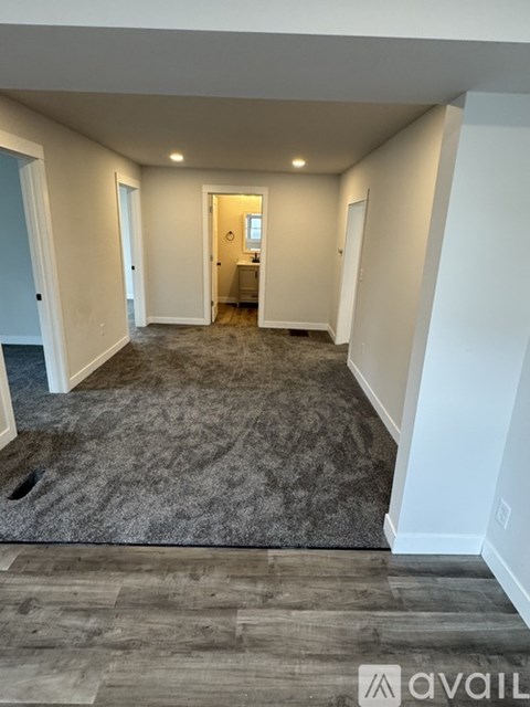 A spacious room with a grey carpet and wooden flooring.