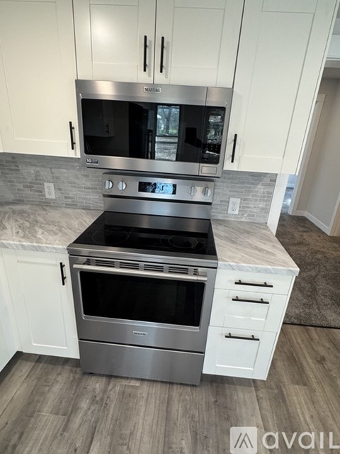 A modern kitchen with a stainless steel oven and white cabinets.