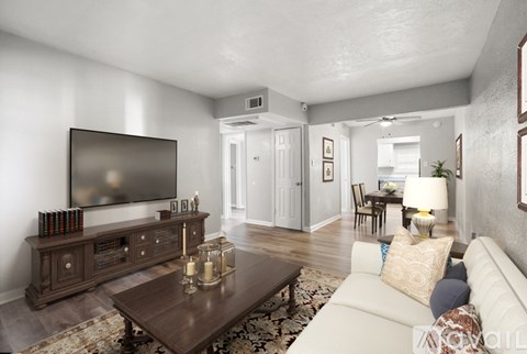 A living room with a white couch, a wooden coffee table, and a flat-screen TV mounted on the wall.