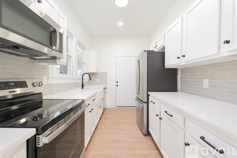 A kitchen with white cabinets and a black refrigerator.
