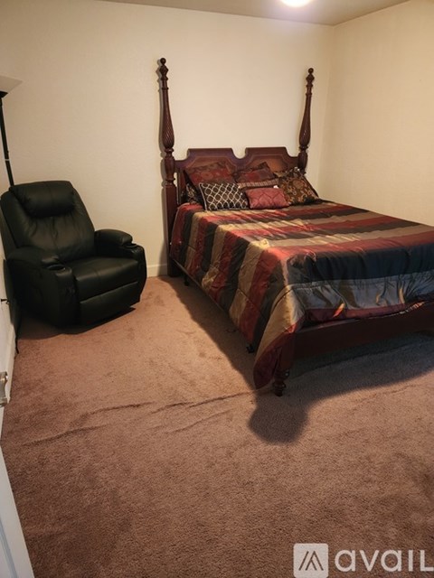 A bedroom with a bed and a chair.