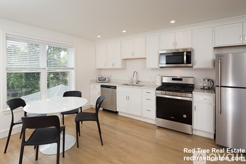 A kitchen with white cabinets and a table with chairs.