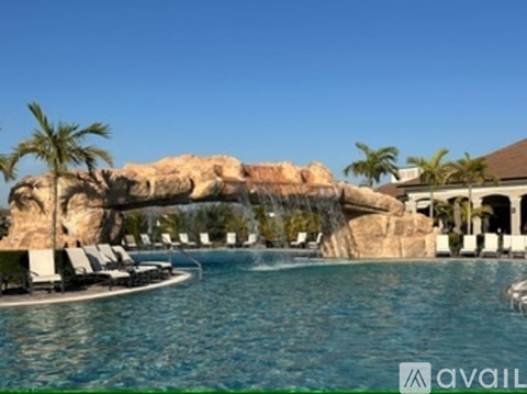 A large pool with a waterfall and lounge chairs.