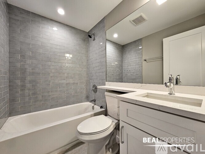 A modern bathroom with a white tub, toilet, and sink.