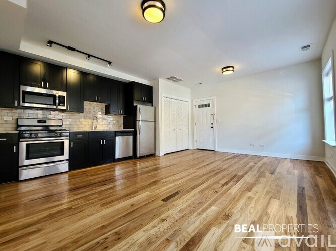 A spacious kitchen with wooden floors and black cabinets.