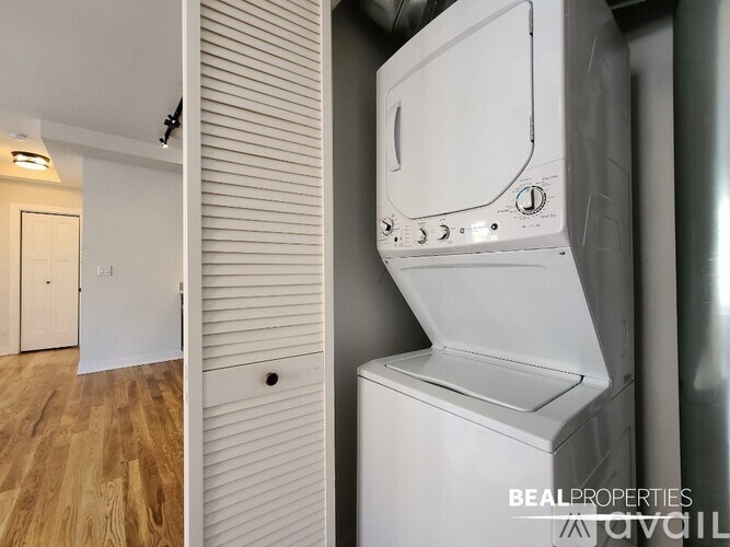 A white dryer is on a stand in a room with wood flooring.