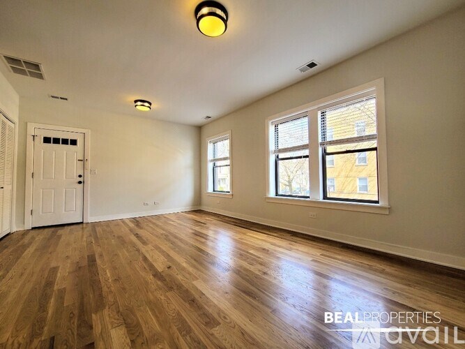 A room with wooden floors and a window with blinds.