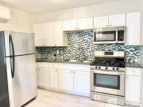 A kitchen with white cabinets and a black and white checkered backsplash.