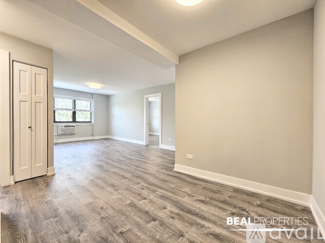 A spacious room with wooden flooring and a door on the left.