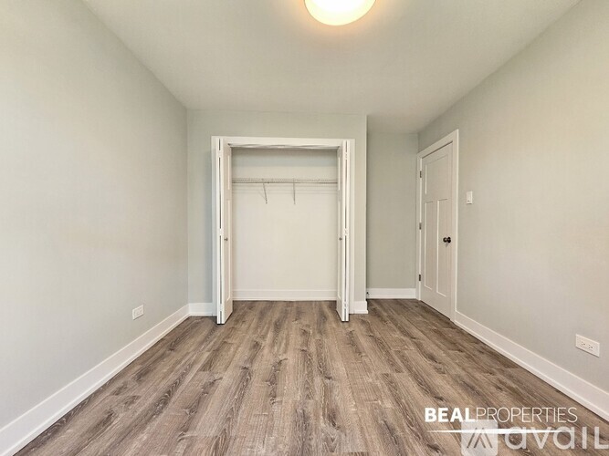 A room with a white door and a wooden floor.