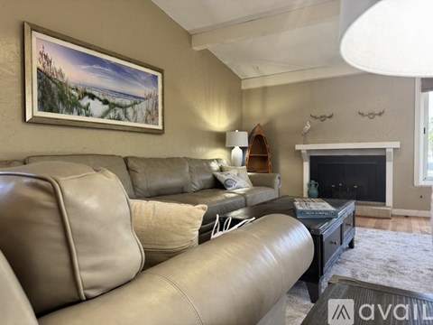 A living room with a grey couch and a painting on the wall.