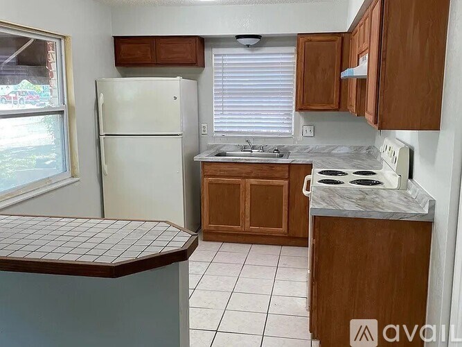 A kitchen with a white refrigerator, wooden cabinets, and a white stove top oven.