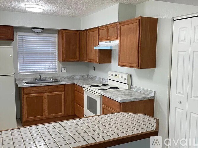 A kitchen with wooden cabinets and a white stove top oven.