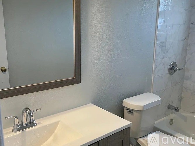 A bathroom with a sink, toilet, and mirror.
